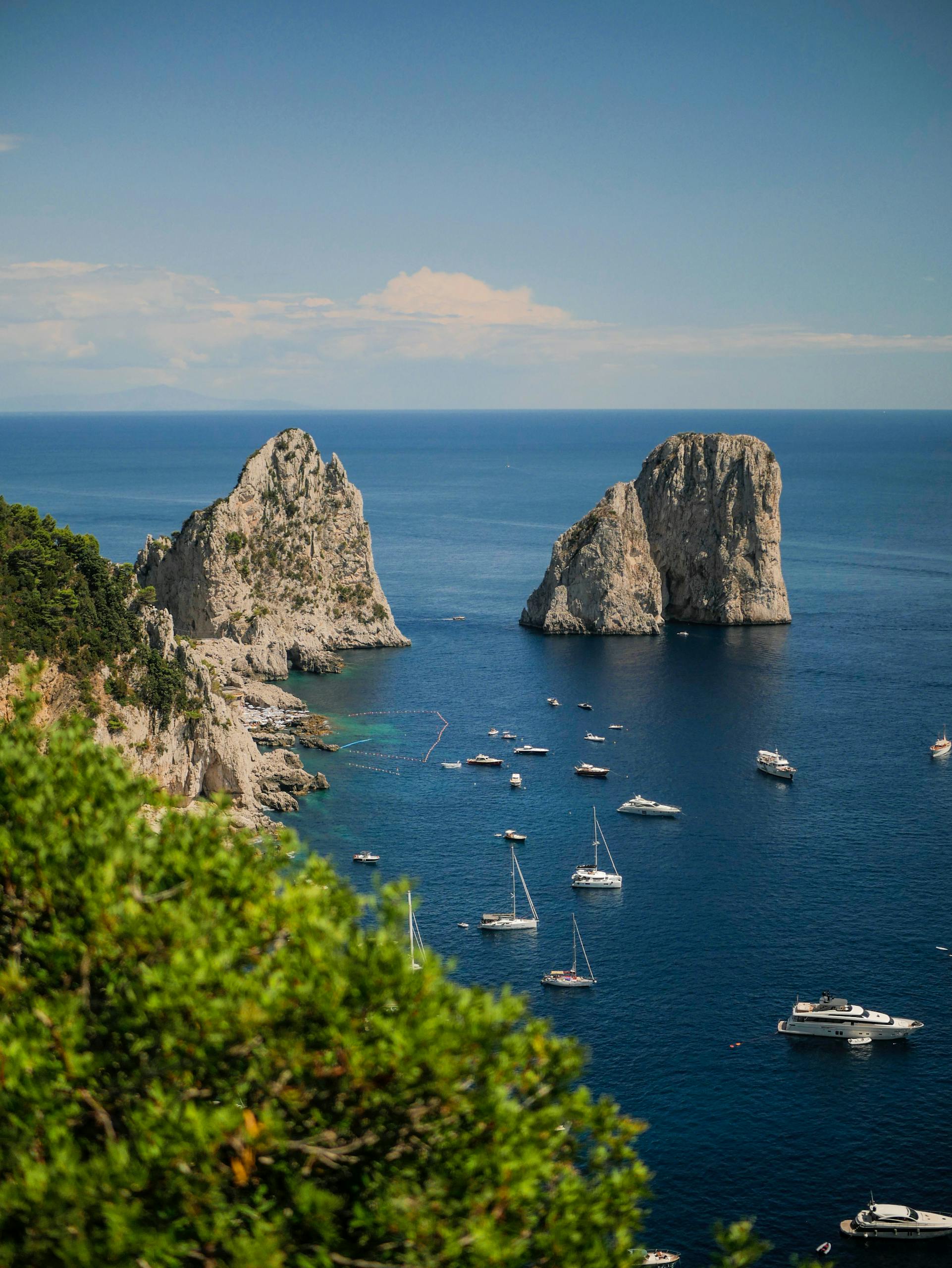 A breathtaking aerial view of the Faraglioni rock formations with yachts in Capri, Italy.