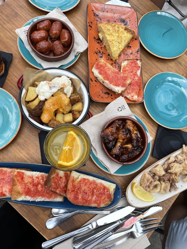 A vibrant display of traditional Spanish tapas served on colorful plates, showcasing diverse flavors.