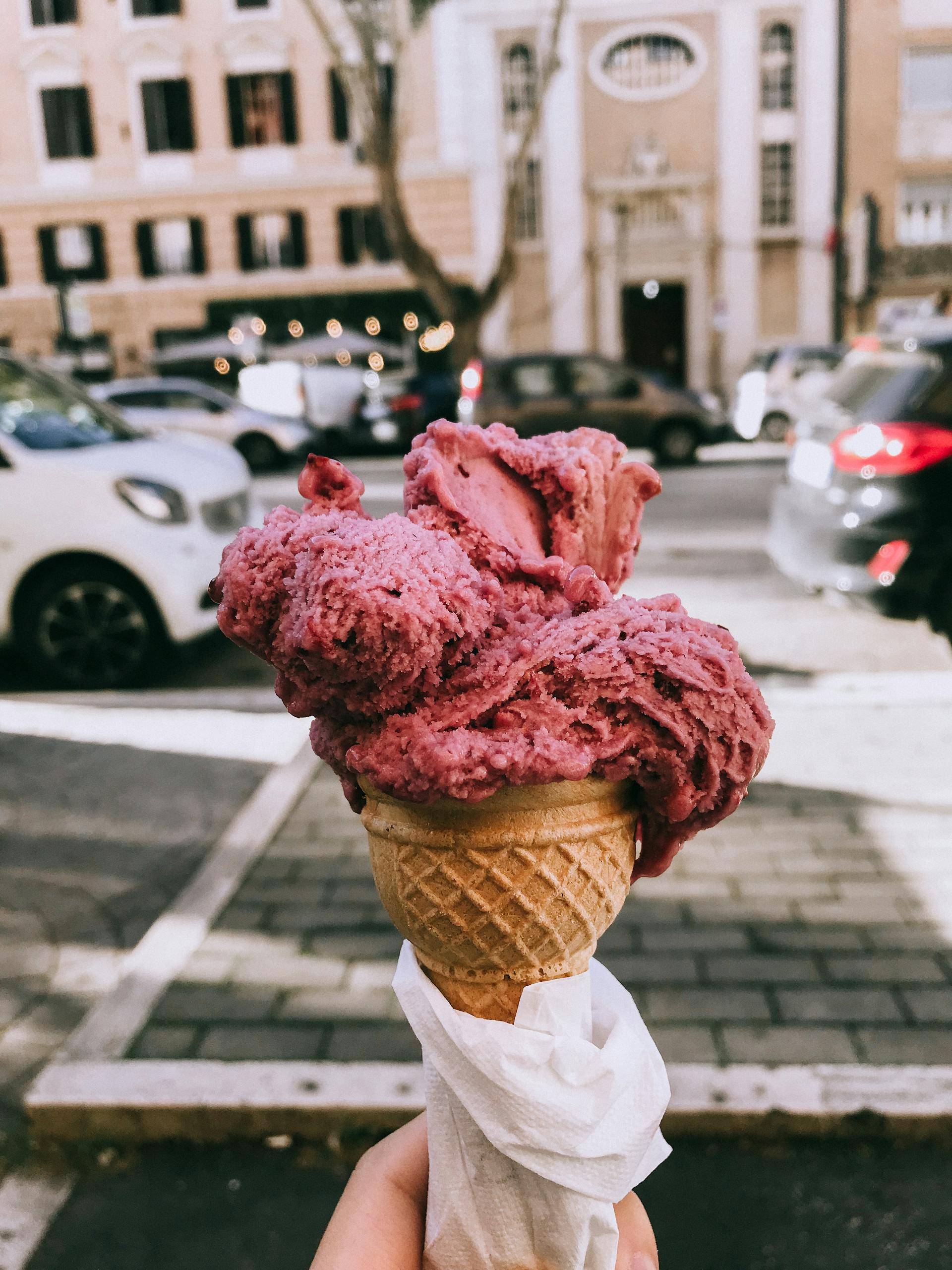 Close-up of a pink gelato cone held outdoors in Rome, Italy. Perfect treat on a sunny day.