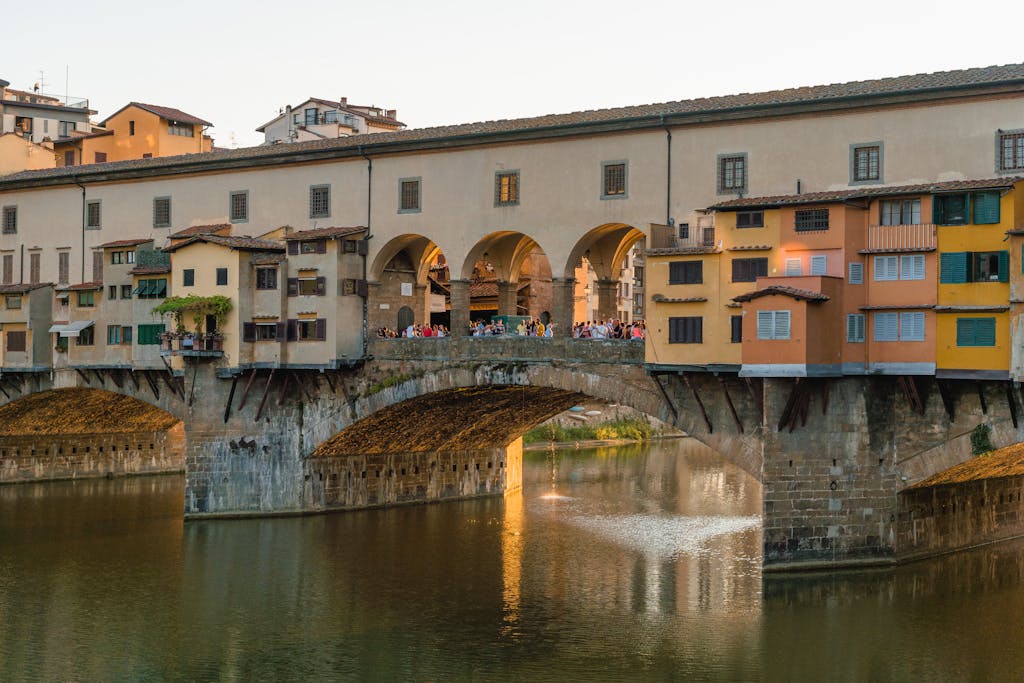 Historic Ponte Vecchio bridge in Florence, Italy, over the Arno River at sunset, famous for its shops.