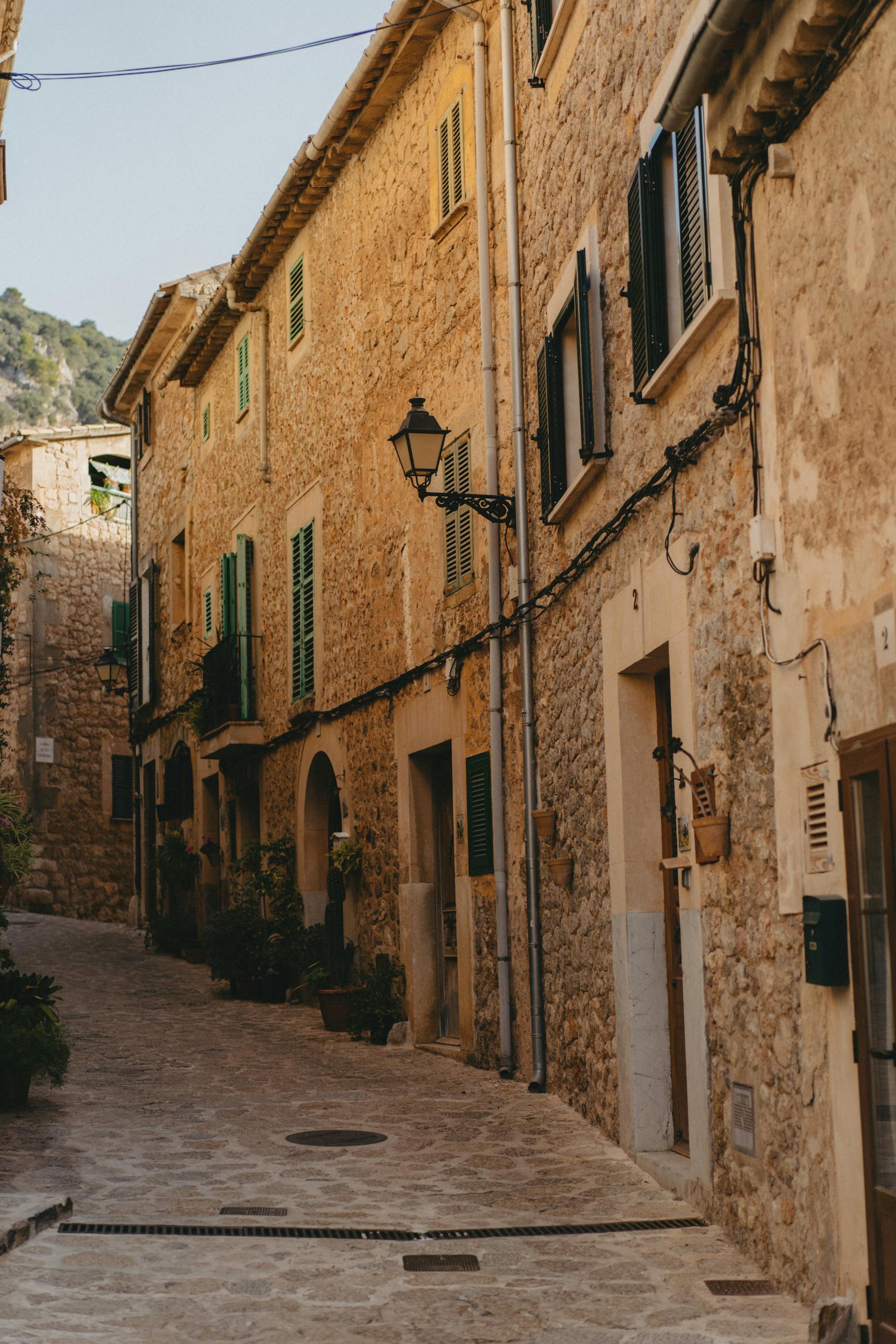 Picturesque cobblestone street in Valldemossa, Spain, showcasing traditional stone houses.
