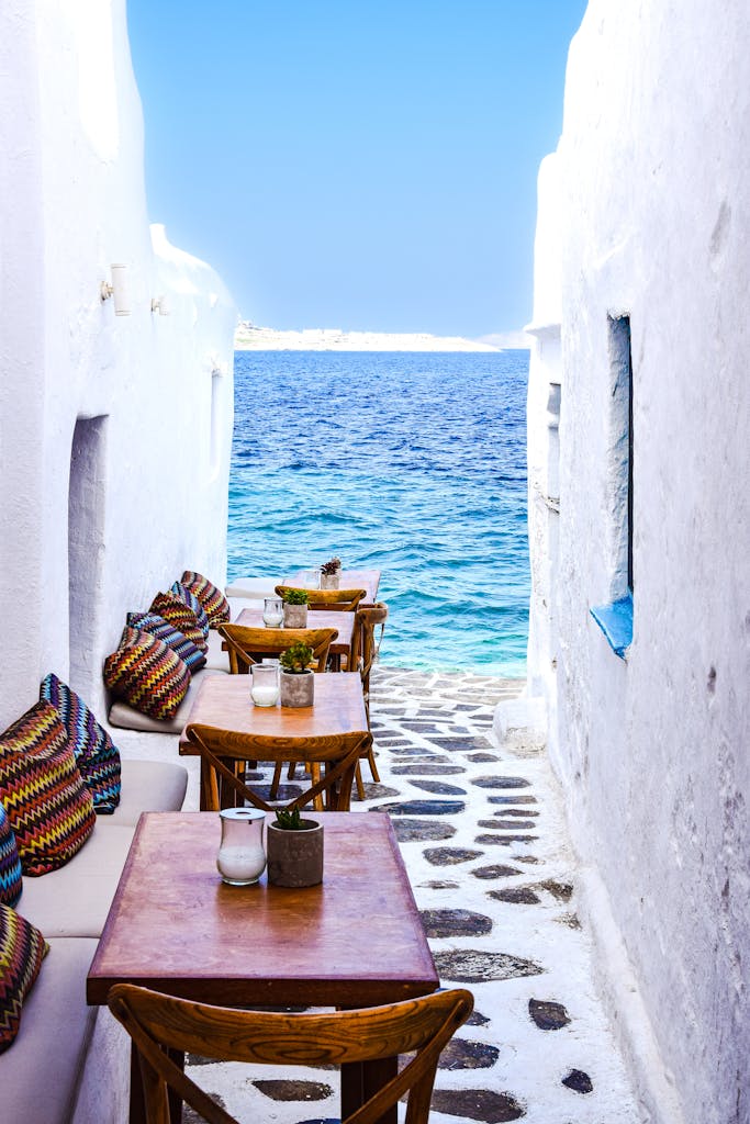 Picturesque Greek alley with tables by the sea, showcasing a serene and inviting setting.