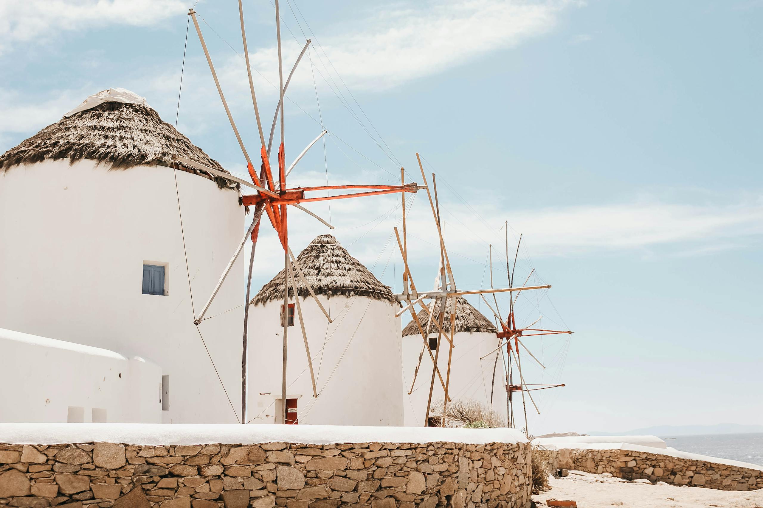 Traditional windmills on the island of Mykonos, Greece, showcasing Cycladic architecture beneath a clear blue sky.