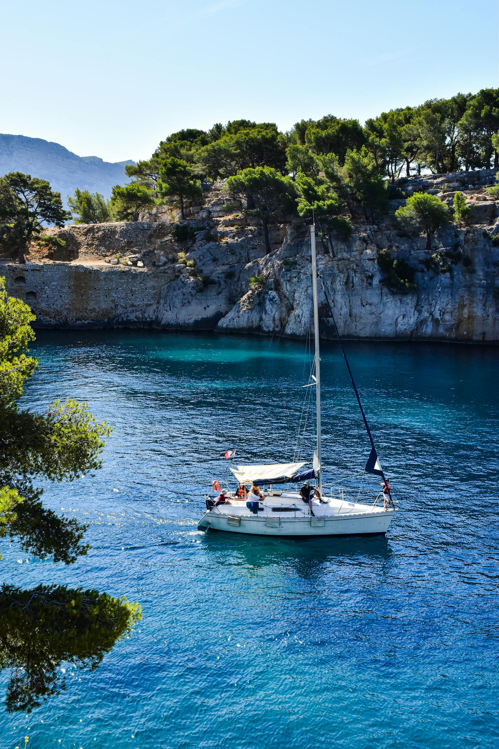 A serene sailboat glides through the azure waters of the French Calanques in Provence-Alpes-Côte d'Azur.