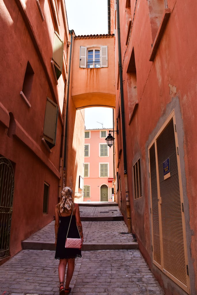 A woman strolls through a picturesque alley in Provence, France.