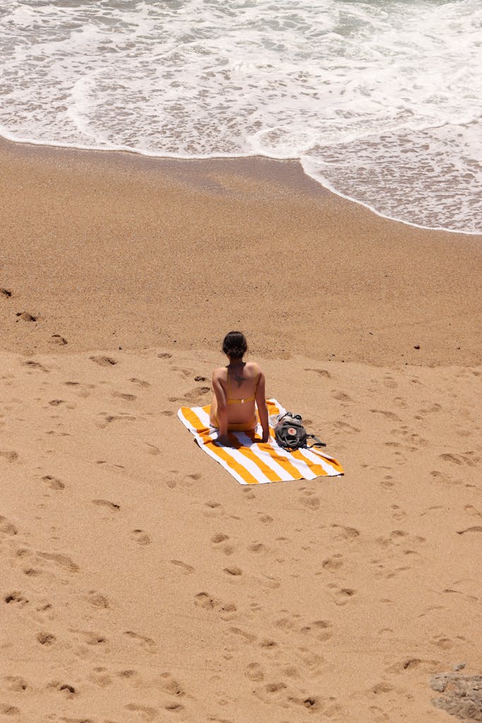 A person relaxing on a sandy beach in Porto, Portugal, with waves rolling in.