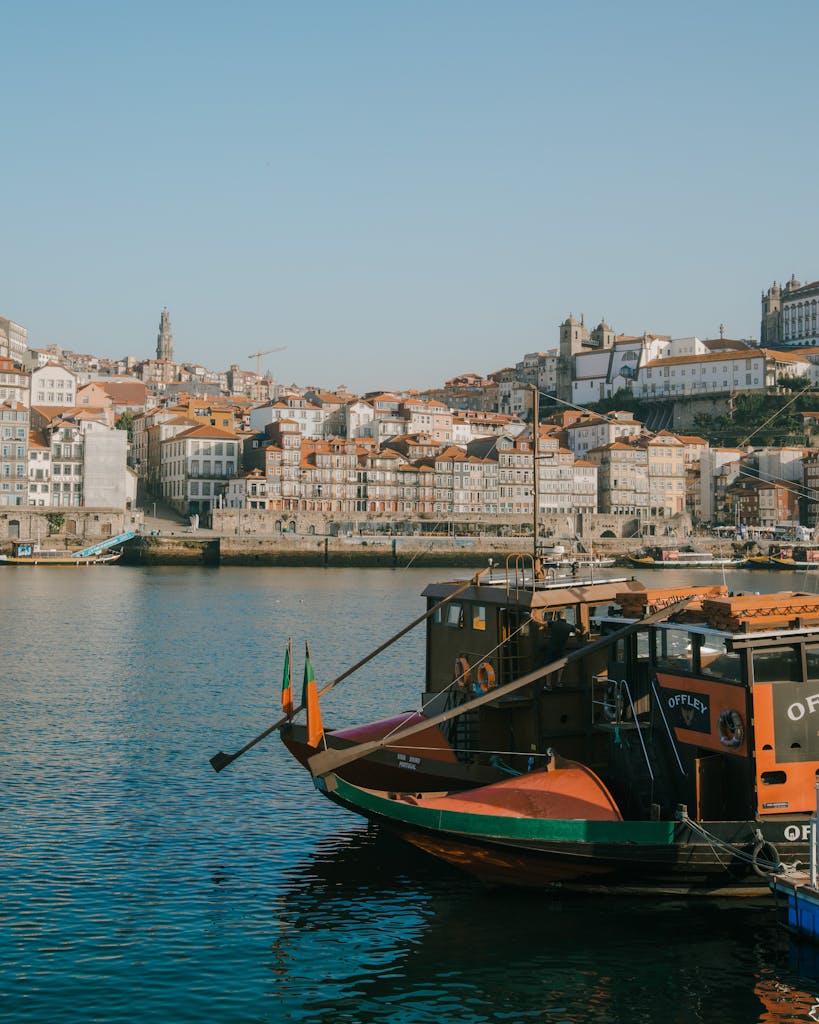 Charming Porto waterfront with traditional boats and historic buildings on a sunny day.