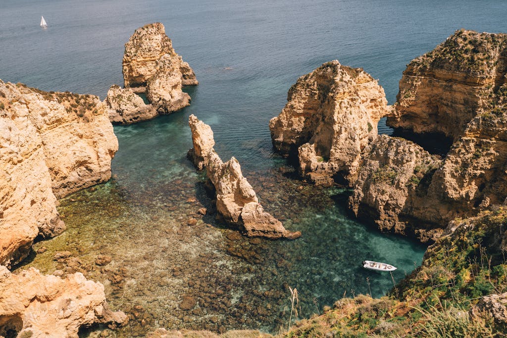 Majestic rock formations towering over turquoise sea water on a sunny day.