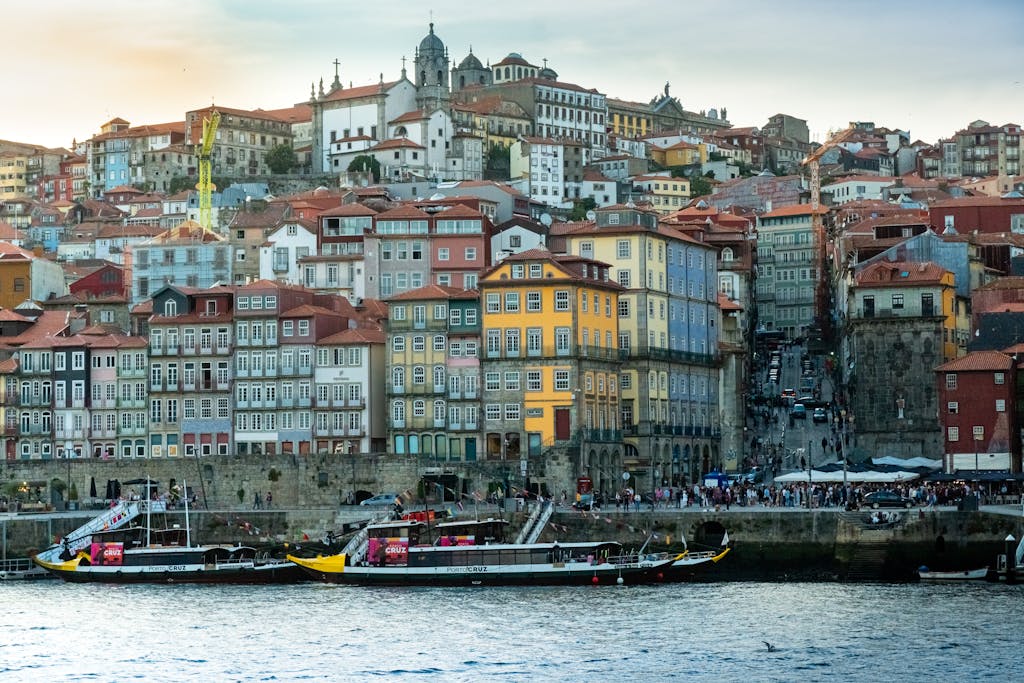 Scenic view of Oporto's historic riverside with colorful buildings and boats at sunset.