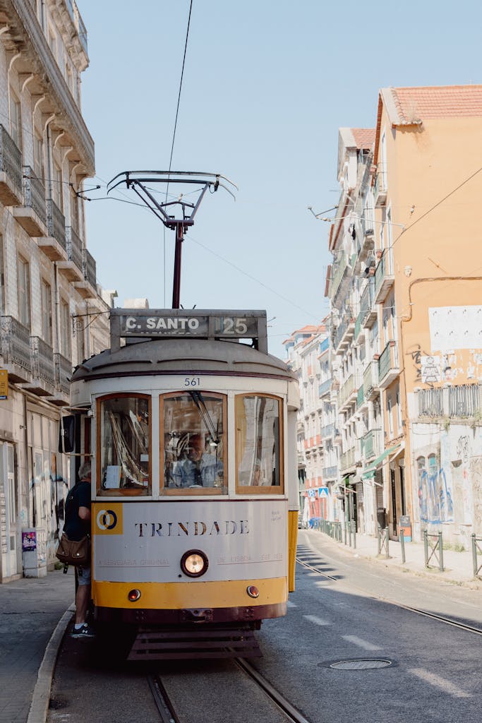 Vintage tram navigating through the vibrant city streets of Lisbon on a sunny summer day.