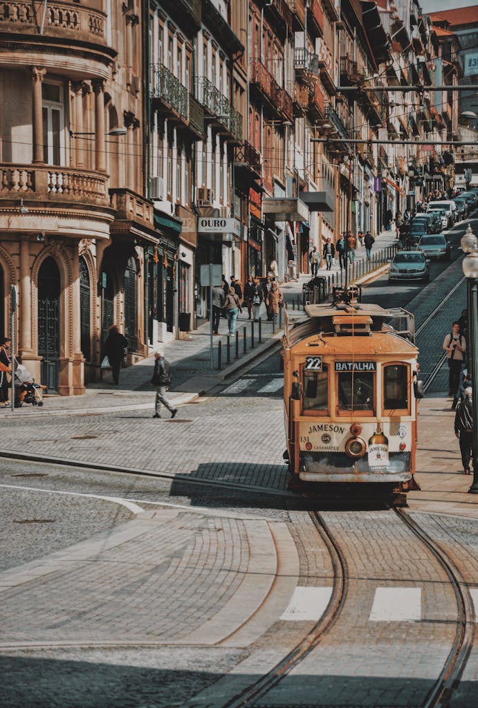 Vintage tram on a cobblestone street in a bustling European city, surrounded by classic architecture.
