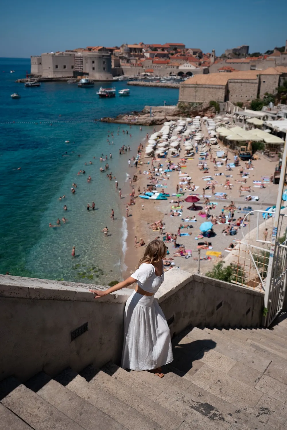 woman on stone steps overlooking a beach