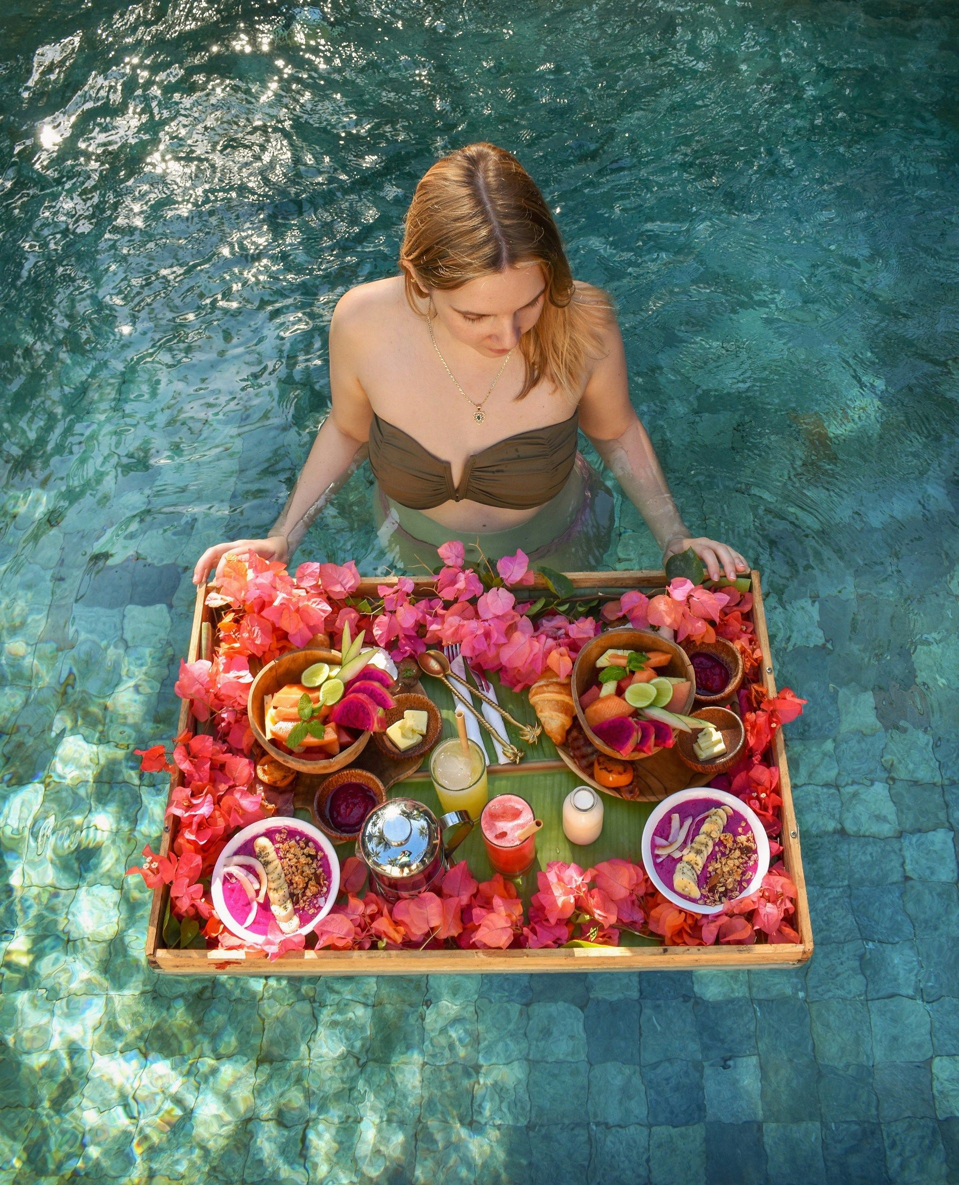 woman with a floating platter of food in a pool