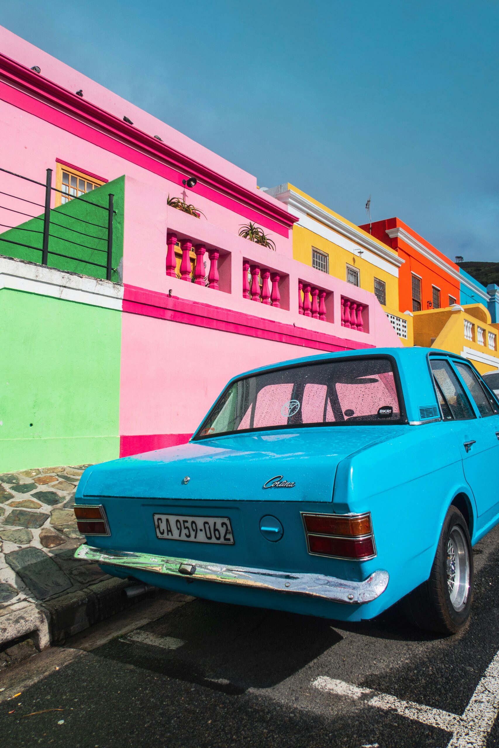 blue car parked besides colorful houses
