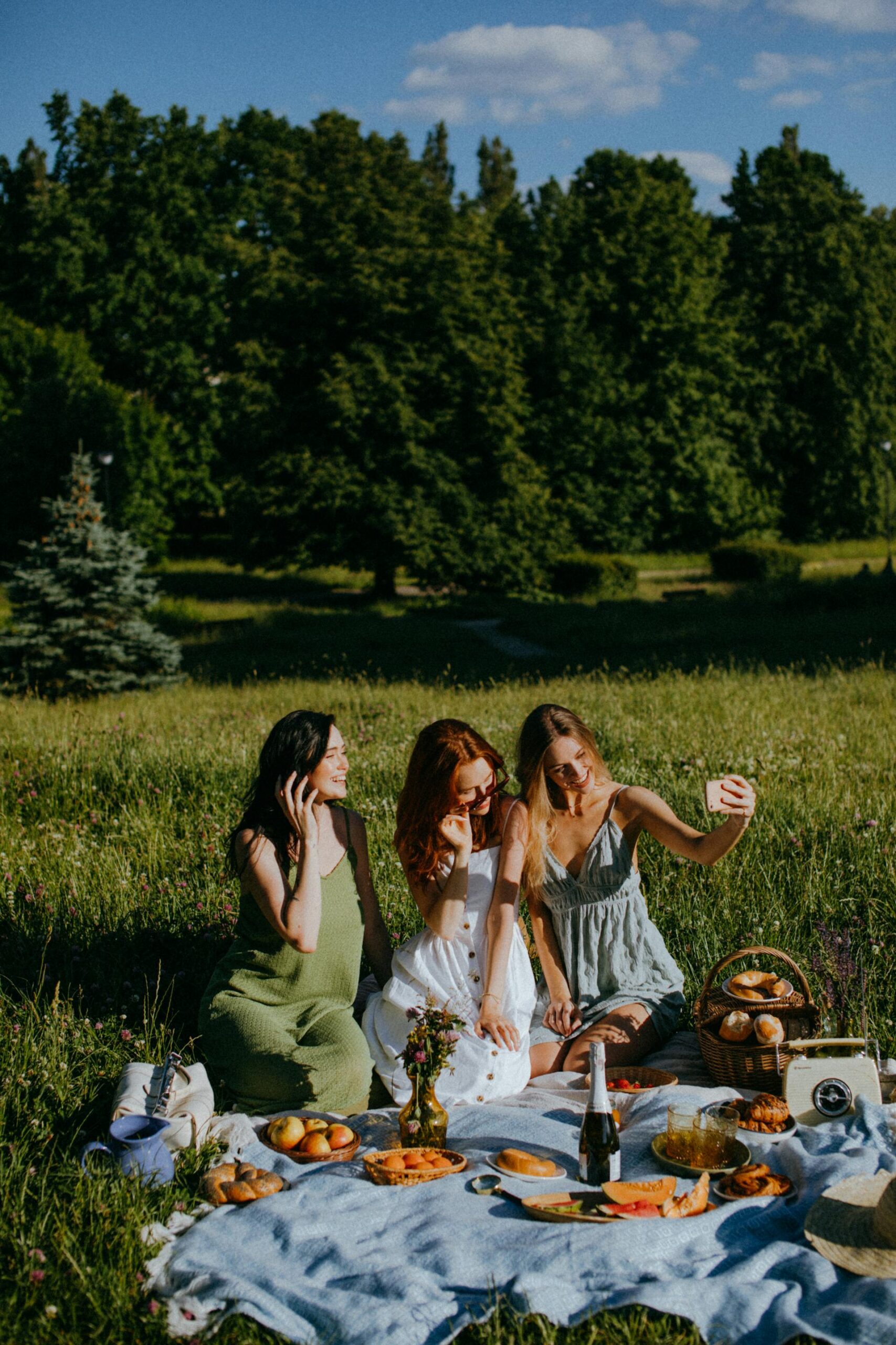 group of women having a picnic outdoors taking photos together